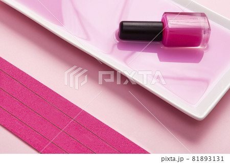 top view pink nail polish dipped in pink liquid with pink nail files and pink background. top view pink nail polish dipped in pink liquid with pink nail files and pink background. 81893131