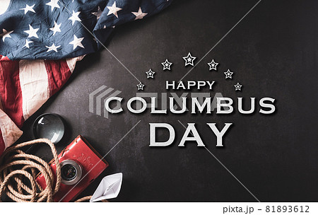 Happy Columbus Day concept. Vintage American flag, compass, paper boat, rope with the text on dark stone background.  Flat lay, top view with copy space. 81893612