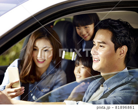 happy asian family with two children traveling by car, mother using cellphone while father driving 81896861