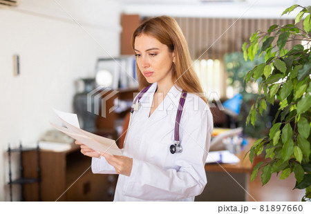 Female doctor in gown standing in hall Female doctor in gown standing in hall 81897660