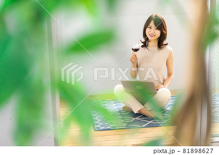 ワインを飲みながらビデオチャットをする若い女性 81898627