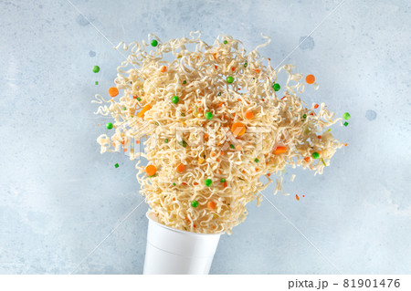 Ramen cup with instant noodles flying out of it 81901476