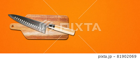 Traditional Japanese gyuto chief knife on a cutting board. Orange banner background Traditional Japanese gyuto chief knife on a cutting board. Orange banner background 81902069