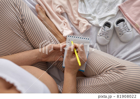 Top view of pregnant woman in the bed preparing baby clothes at home 81908022