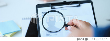 Employee examines resume application form under magnifying glass 81908727
