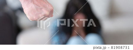 Man stands with fist clenched against background of crying woman Man stands with fist clenched against background of crying woman 81908731