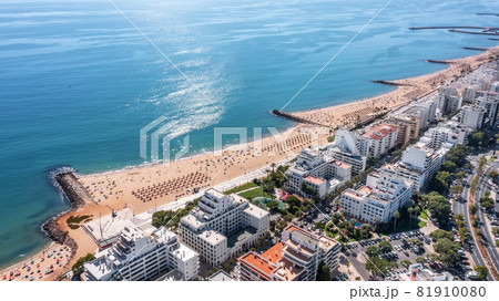 Beautiful aerial cityscapes of the tourist Portuguese city of Quarteira. On the seashore during the beach season with tourists who are sunbathing. 81910080