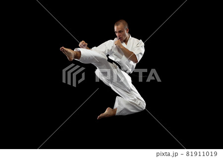 Full-length portrait. One young karate sportsman training isolated over black background 81911019