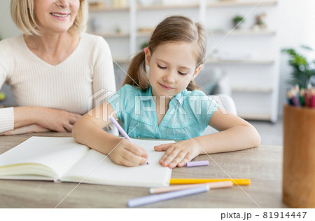 Portrait granny and granddaughter drawing with markers at home Portrait granny and granddaughter drawing with markers at home 81914447