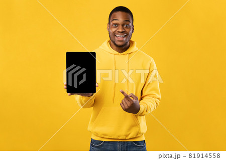 Black Man Pointing At Digital Tablet Empty Screen, Yellow Background Black Man Pointing At Digital Tablet Empty Screen, Yellow Background 81914558