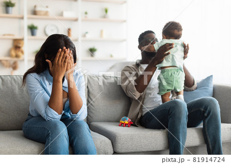 Tired African American mom crying, dad playing with kid Tired African American mom crying, dad playing with kid 81914724
