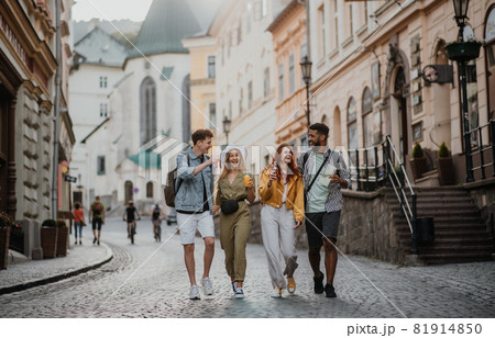 Front view of group of happy young people with drinks outdoors on street on town trip, laughing. Front view of group of happy young people with drinks outdoors on street on town trip, laughing. 81914850