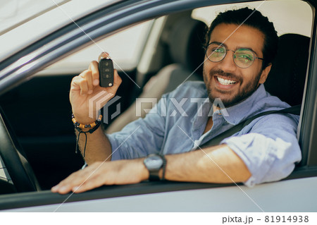 Cheerful middle-eastern long-haired guy showing car key Cheerful middle-eastern long-haired guy showing car key 81914938