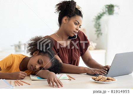 Bored teen girl sitting by her working mom, kitchen interior 81914955