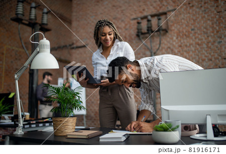 Cheerful young businesspeople with laptop working in office, cooperation concept. Cheerful young businesspeople with laptop working in office, cooperation concept. 81916171