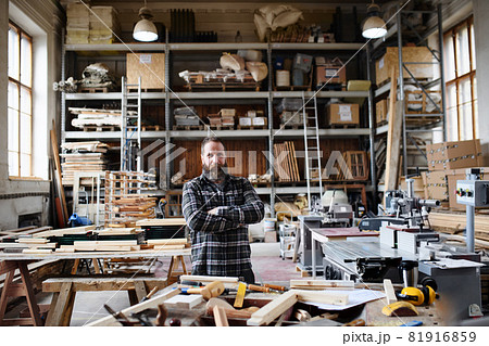 Portrait of mature male carpenter standing in carpentery workshop, looking at camera. Small business concept. 81916859