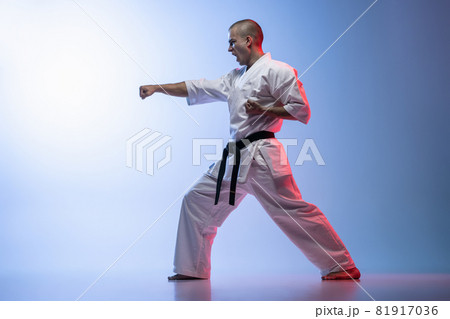 Side view image sportsman standing in a fight pose isolated over gradiet white blue background. Karate, judo, taekwondo sport 81917036