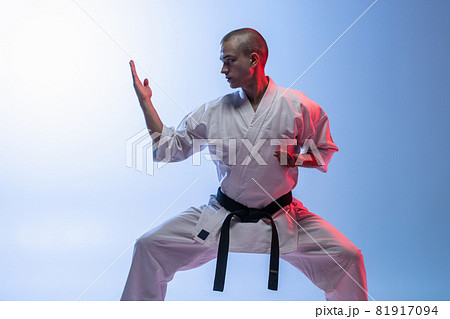 Cropped portrait of caucasian sportsman standing in a fight pose isolated over gradiet white blue background. Karate, judo, taekwondo sport 81917094