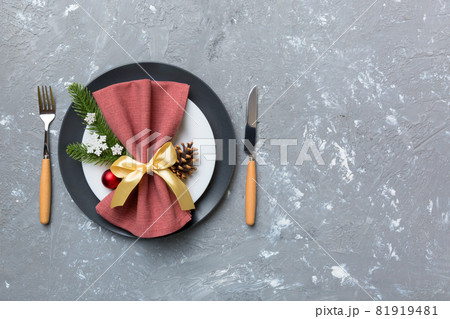 Christmas table place setting with christmas decor and plates, kine, fork and spoon. Christmas holiday background. Top view with copy space Christmas table place setting with christmas decor and plates, kine, fork and spoon. Christmas holiday background. Top view with copy space 81919481
