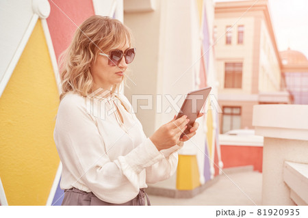 Pretty young woman texting by tablet. Happy female person outdoors. Summer 81920935
