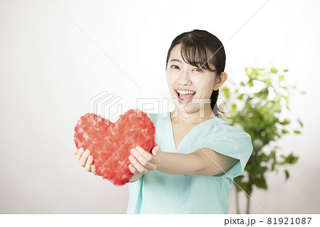 笑顔で赤いハートを持つ女性看護師 81921087