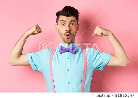 Image of funny guy with moustache and bow-tie, showing muscles, flexing biceps and looking surprised at camera, standing in disbelief on pink background Image of funny guy with moustache and bow-tie, showing muscles, flexing biceps and looking surprised at camera, standing in disbelief on pink background 81925547