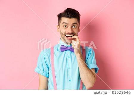 Excited and tempted young guy wants something, biting fingernail with temptation looking at camera, choosing product, standing over pink background 81925640