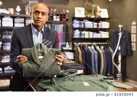 Seller offering suit jacket in menswear boutique Seller offering suit jacket in menswear boutique 81930045