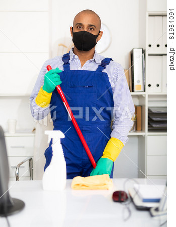 Portrait of professional male cleaner in medical mask looking at camera in office 81934094