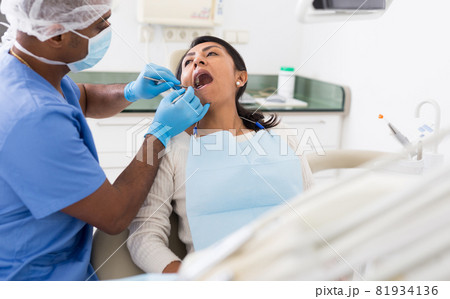 Male dentist treating female patient in dental clinic 81934136