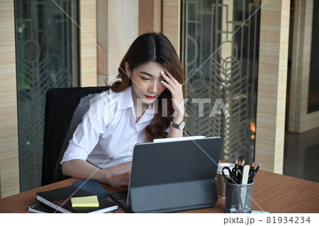 Stressed businesswoman holding her head while checking information on computer tablet. 81934234