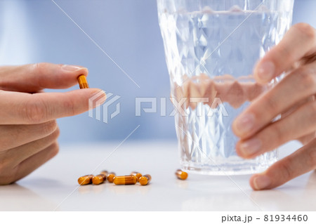 カプセル剤を飲もうとする男性の手元 81934460