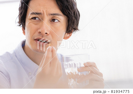 カプセル剤を水で飲もうとする男性 81934775