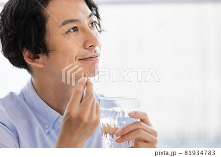 カプセル剤を水で飲もうとする男性 81934783
