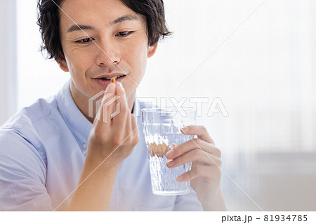 カプセル剤を水で飲もうとする男性 81934785