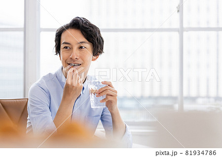 カプセル剤を水で飲もうとする男性 81934786