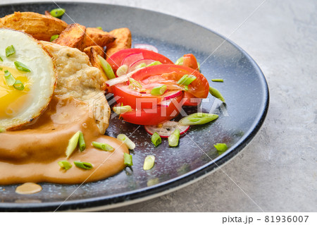 Closeup view of chopped pork sirloin with fried potato wedges, egg, tomato and radish 81936007