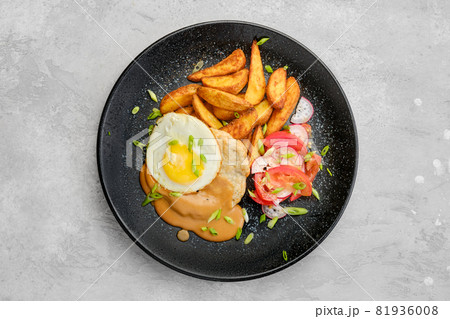 Top view of chopped pork sirloin with fried potato wedges, egg, tomato and radish 81936008