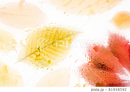 Yellow autumn leaves behind foggy glass with drops of water and rain. Fall abstract background. Yellow autumn leaves behind foggy glass with drops of water and rain. Fall abstract background. 81938592