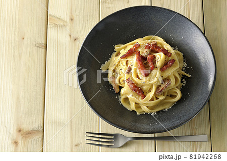 カリカリに焼いたベーコン入りフェットチーネのカルボナーラとフォークを俯瞰で撮影 81942268
