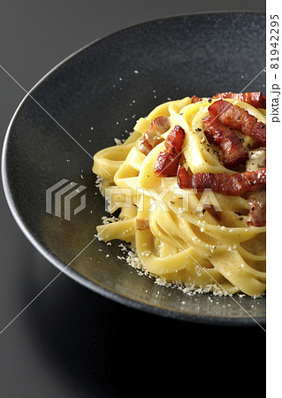 カリカリに焼いたベーコン入りフェットチーネのカルボナーラを黒背景で撮影 81942295