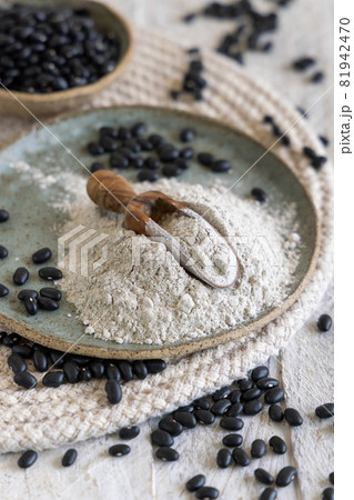 Plate with black beans flour with a wooden scoop 81942470