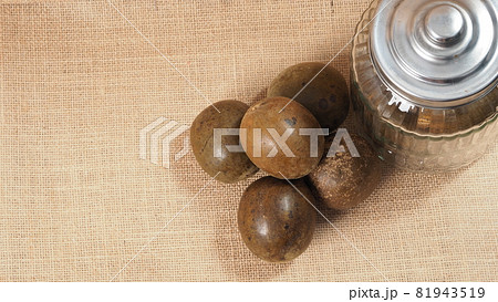 Monk fruit or Luo Han Guo. Dried fruits for healthy sweetener drink. Natural herbal remedy and glass bottle background. Monk fruit drink for who concern health and sugar substitute. Monk fruit or Luo Han Guo. Dried fruits for healthy sweetener drink. Natural herbal remedy and glass bottle background. Monk fruit drink for who concern health and sugar substitute. 81943519