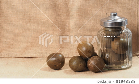 Monk fruit or Luo Han Guo. Dried fruits for healthy sweetener drink. Natural herbal remedy and glass bottle background. Monk fruit drink for who concern health and sugar substitute. Monk fruit or Luo Han Guo. Dried fruits for healthy sweetener drink. Natural herbal remedy and glass bottle background. Monk fruit drink for who concern health and sugar substitute. 81943538