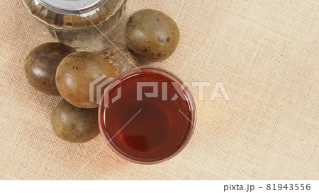Monk fruit or Luo Han Guo. Dried fruits for healthy sweetener drink. Natural herbal remedy and glass bottle background. Monk fruit drink for who concern health and sugar substitute. Monk fruit or Luo Han Guo. Dried fruits for healthy sweetener drink. Natural herbal remedy and glass bottle background. Monk fruit drink for who concern health and sugar substitute. 81943556