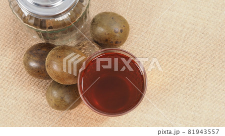 Monk fruit or Luo Han Guo. Dried fruits for healthy sweetener drink. Natural herbal remedy and glass bottle background. Monk fruit drink for who concern health and sugar substitute. Monk fruit or Luo Han Guo. Dried fruits for healthy sweetener drink. Natural herbal remedy and glass bottle background. Monk fruit drink for who concern health and sugar substitute. 81943557