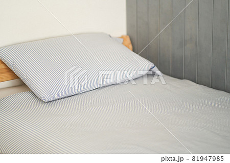 The bed is at the back of the room. The bed is made up. Gray color. High quality photo The bed is at the back of the room. The bed is made up. Gray color. High quality photo 81947985