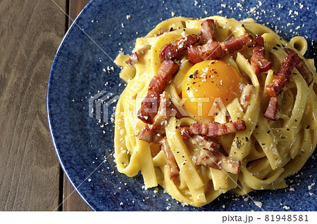 卵黄やカリカリに焼いたベーコンが入っているフェットチーネのカルボナーラを俯瞰で撮影 81948581