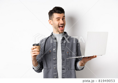 Happy male worker drinking coffee and work with laptop, winking at camera, standing on white background Happy male worker drinking coffee and work with laptop, winking at camera, standing on white background 81949053