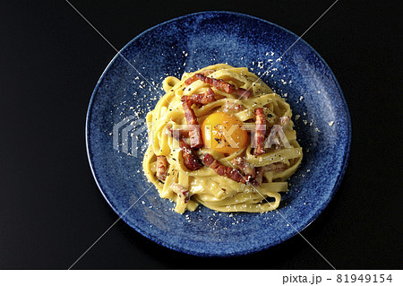 卵黄やカリカリに焼いたベーコンが入っているフェットチーネのカルボナーラを黒背景で俯瞰撮影 卵黄やカリカリに焼いたベーコンが入っているフェットチーネのカルボナーラを黒背景で俯瞰撮影 81949154